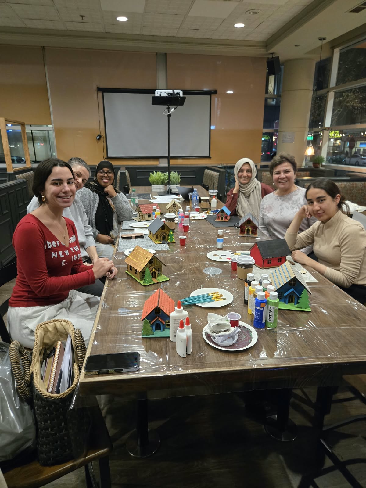 Participants gathered around a shared table with their colourful painted wooden house models at Crafted Calm's first public workshop