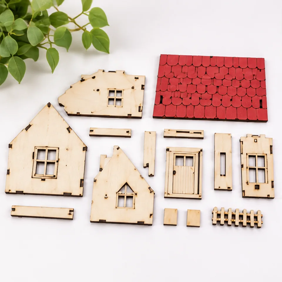 Illustrative laser-cut plywood cottage pieces with dark cut edges laid out before assembly