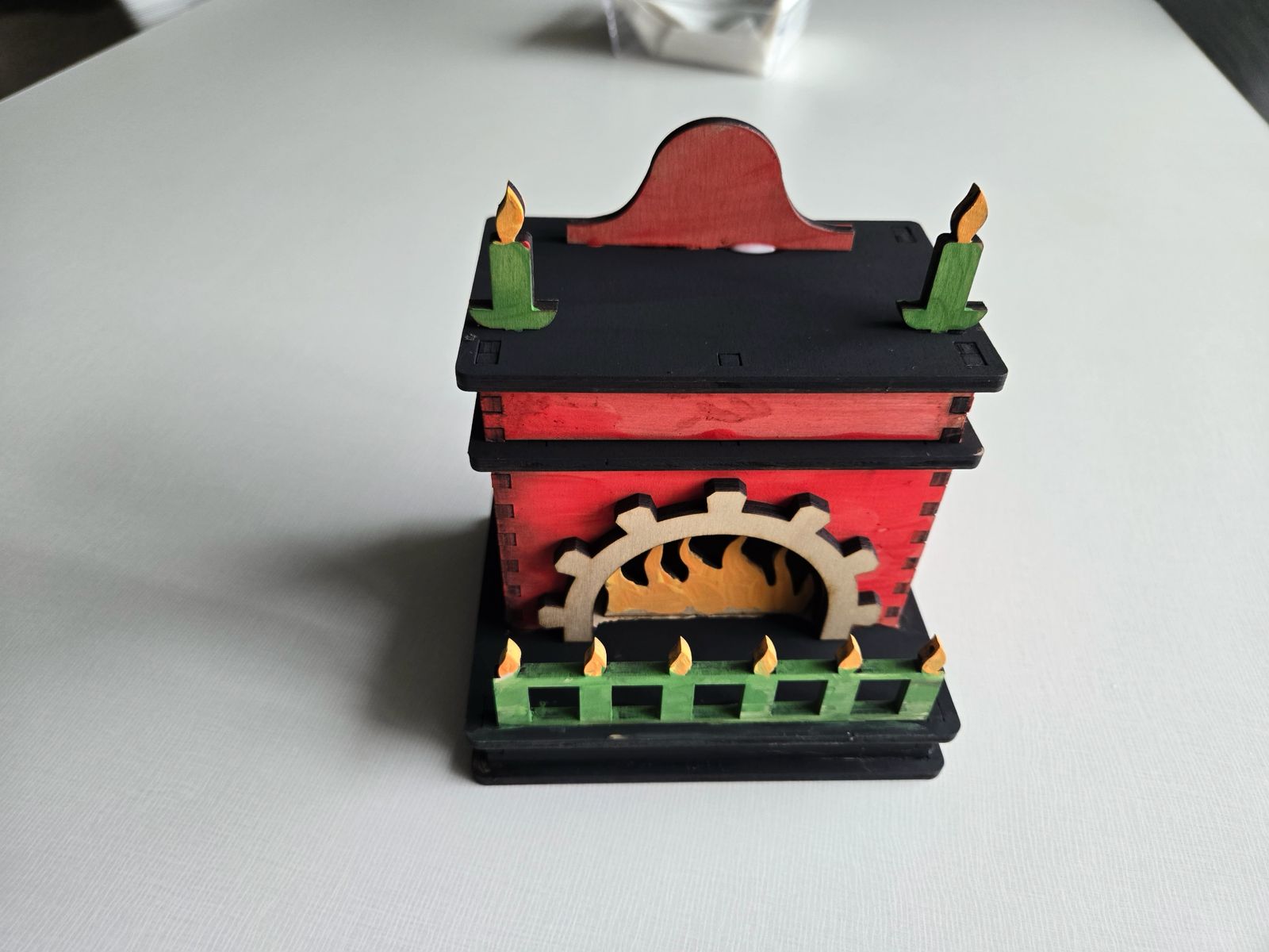 Hand-painted red and black plywood fireplace with green candle details and visible laser-cut joints